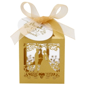 Detail of laser-cut golden wedding favor box with ribbon and thank you tag