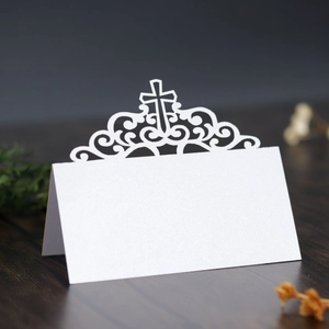Détail de marque-place blanc découpé au laser avec croix et motifs volutes élégants