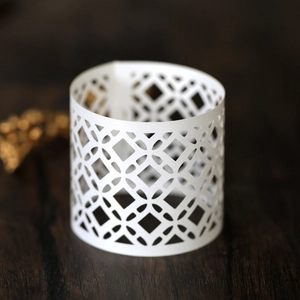 Close-up of white laser-cut napkin ring with intricate geometric镂空 diamond pattern
