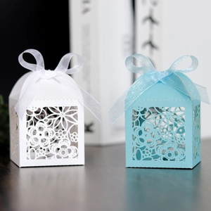 Close-up of laser-cut floral favor boxes with satin ribbons for weddings and parties