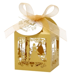 Close-up of laser-cut wedding favor box with gold ribbon and thank you tag