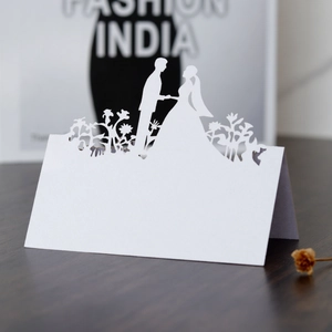 Macro detail of laser-cut wedding place card with elegant bride and groom silhouette