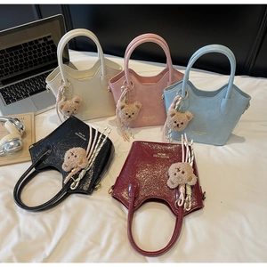 Cinque borse a secchiello vintage in vari colori con ciondoli orsetto su un letto bianco