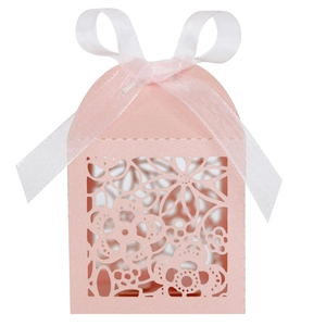 Detail of pink laser-cut wedding favor box with floral patterns and a white ribbon bow