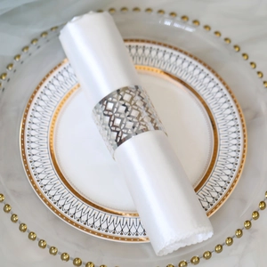Detail of silver hollow geometric napkin ring on elegant white silk and fine dinnerware