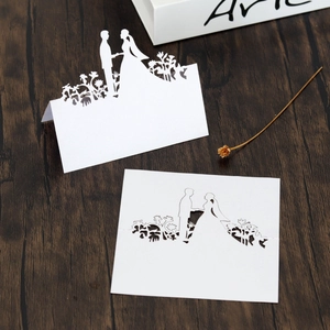 Detail of laser-cut wedding place cards featuring floral silhouette on white paper