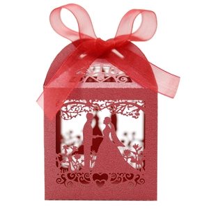 Detail of red laser-cut wedding favor box with romantic silhouette and silk ribbon