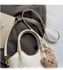 Dettaglio borsa a secchiello bianca con texture a pieghe e ciondolo a forma di orsetto