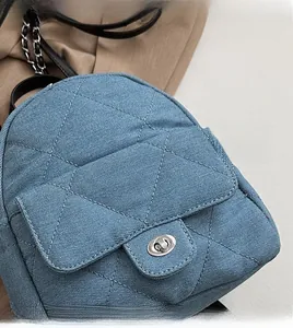 Detailed close-up of blue denim quilted texture and silver twist-lock on shoulder bag