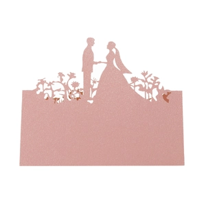 Macro shot of rose gold glitter wedding place card with laser-cut silhouette of newlyweds