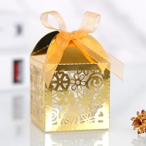 Détail de la découpe laser florale sur boîte cadeau dorée avec ruban en soie orange
