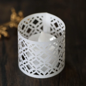 Detailed view of white laser-cut paper lampshade with diamond pattern and LED candle light