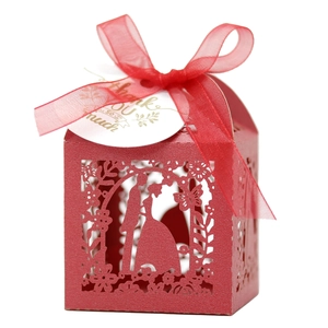 Detail of red hollow laser-cut wedding candy box with bride groom silhouette and ribbon