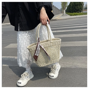 Detail of hollow woven tote bag with red and white printed silk scarf on street