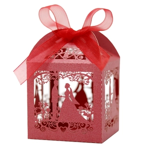 Detail of red laser-cut wedding candy box with bride and groom silhouette and ribbon
