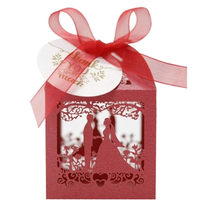 Close-up of red laser-cut wedding candy box with bride and groom silhouette and ribbon