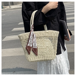 Close-up of beige hollow-out woven tote bag with a decorative printed silk scarf handle