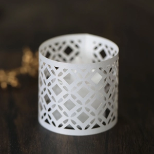 Detailed close-up of white laser-cut hollow paper lampshade with geometric diamond patterns