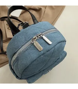 Detail view of double silver metal zippers and diamond quilted denim on blue tote bag