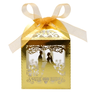 Detail of laser-cut gold wedding favor box with groom and bride silhouette and gold ribbon