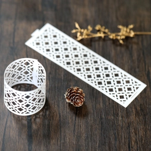 Close-up of white laser-cut hollow paper napkin ring with elegant geometric pattern