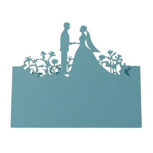 Macro view of blue laser-cut wedding place card featuring a bride and groom silhouette