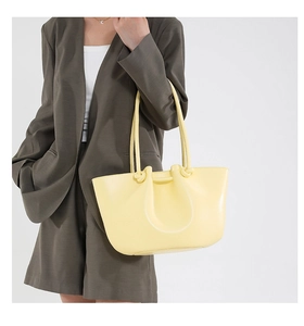 Dettaglio di una borsa tote in pelle giallo chiaro con tracolla annodata sul modello