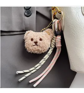 Dettaglio portachiavi a forma di orsetto su borsa bianca con accenti dorati lucidi