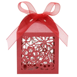 Detail of red laser-cut wedding favor box featuring intricate patterns and silk ribbon bow