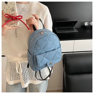 Detail of light blue quilted denim shoulder bag with silver turn-lock and black straps