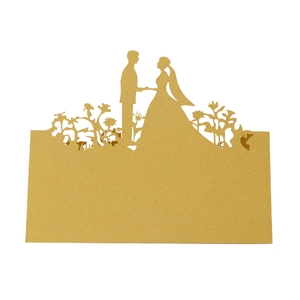 Detail of laser-cut gold wedding table card featuring silhouettes of a bride and groom