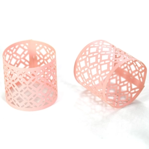 Detailed close-up of pink hollow-out napkin rings with elegant laser-cut geometric patterns