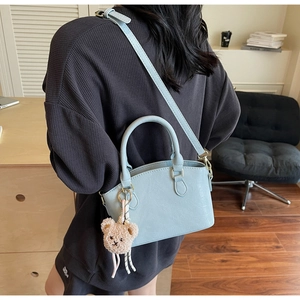 Detail of light blue crocodile pattern bucket bag with cute brown bear charm