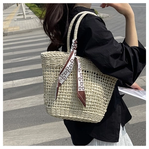 Close-up of beige hollow-out woven tote bag with a decorative cartoon bear scarf