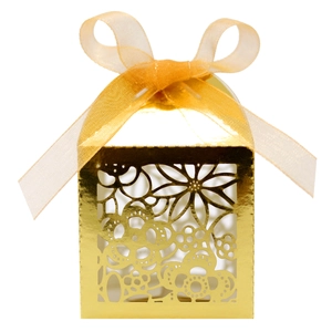 Close-up of golden laser-cut wedding favor box with intricate floral patterns and ribbon