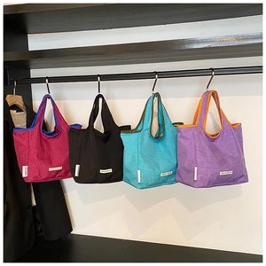 Macro detail of high-quality nylon tote bags in four vibrant colors on a metal rack