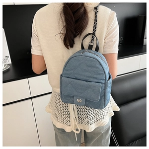 Detail of light blue denim mini backpack with quilted pattern and chain strap on shoulder