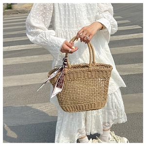 Detailed hollow-out woven texture of a straw tote bag with a decorative silk scarf accessory