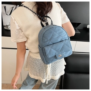 Detail of light blue denim mini backpack with quilted pattern and silver turn-lock clasp