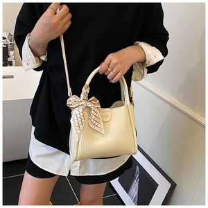 Vue détaillée du sac seau crème à motif croco avec foulard à carreaux sur la poignée