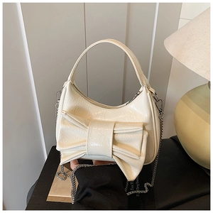 Détail du sac croissant crème en cuir verni plissé avec grand nœud décoratif