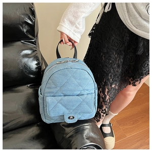 Close-up of a mini denim backpack with quilted pattern and silver hardware in hand