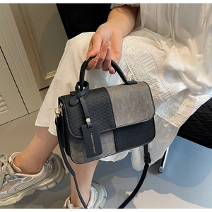 Detail of color-block crossbody bag with grey suede and black woven texture panels