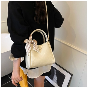 Détail d'un sac à main crème gaufré crocodile avec foulard décoratif et bandoulière