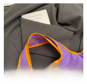 Close-up of purple nylon tote bag with orange piping handle on gray suit background