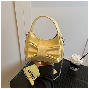 Détail du sac croissant jaune pâle brillant avec grand nœud et bandoulière chaîne