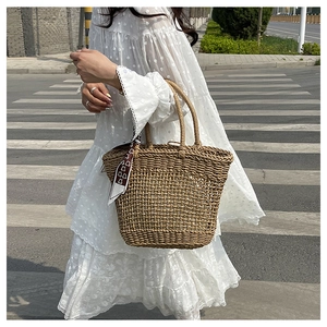 Detail view of woven hollow tote bag featuring a decorative printed silk scarf on handle
