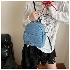 Detail view of mini blue denim backpack with quilted pattern and silver turn-lock closure