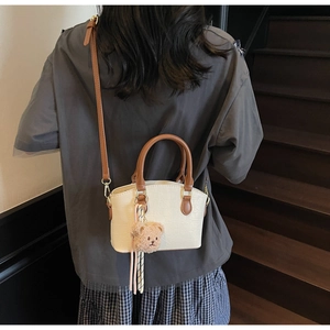 Detail of cream crocodile embossed bucket bag with brown handles and a cute bear charm