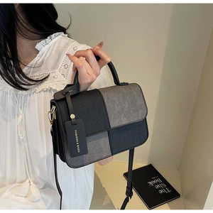 Detail of grey and black patchwork handbag with grain texture and fashion tag